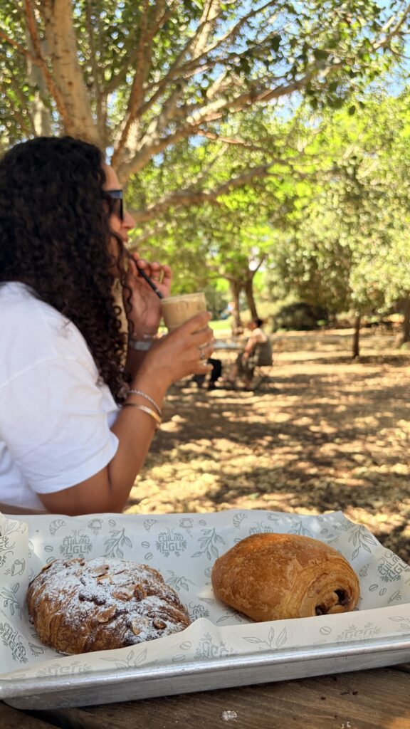 ישיבה בצל העצים בקפה בחורשה עם קפה ומאפים